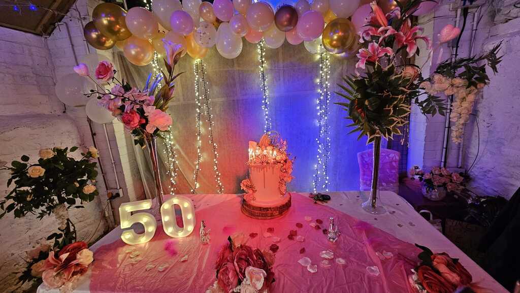 50th birthday party setup with lights, balloons and cake